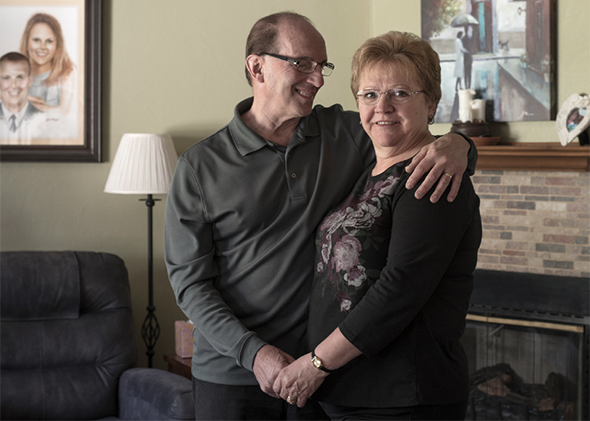 Vivian and Michael Scholze stand in their living room in Harrison City, Pa. In 2017, after taking ineffective medication for years, Vivian went to UPMC for a deep brain stimulation implant to relieve her essential tremor.